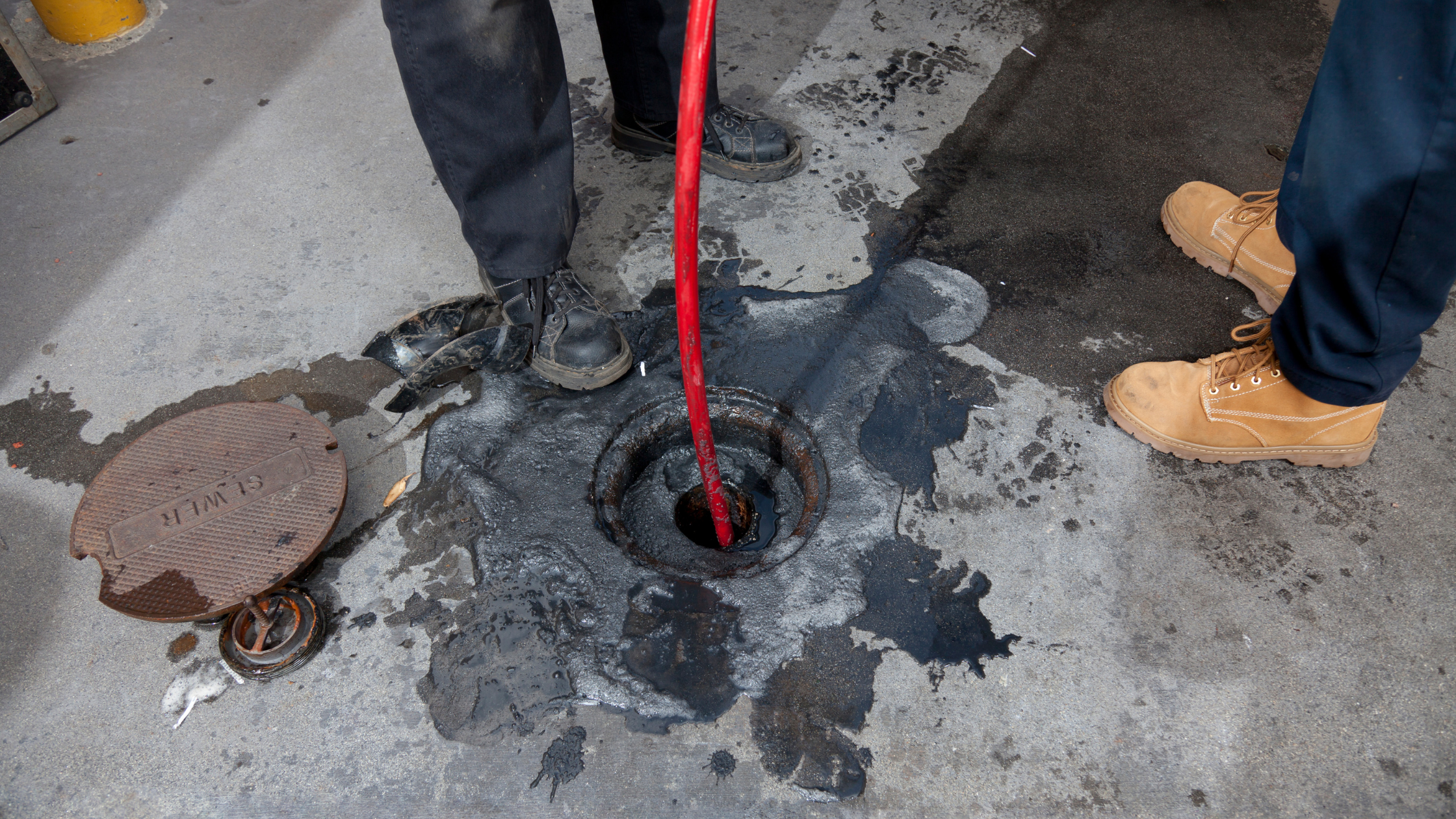 Drain Bros llc team fixes a sewer emergency, cleaning up a black liquid spill and working safely to solve the problem.