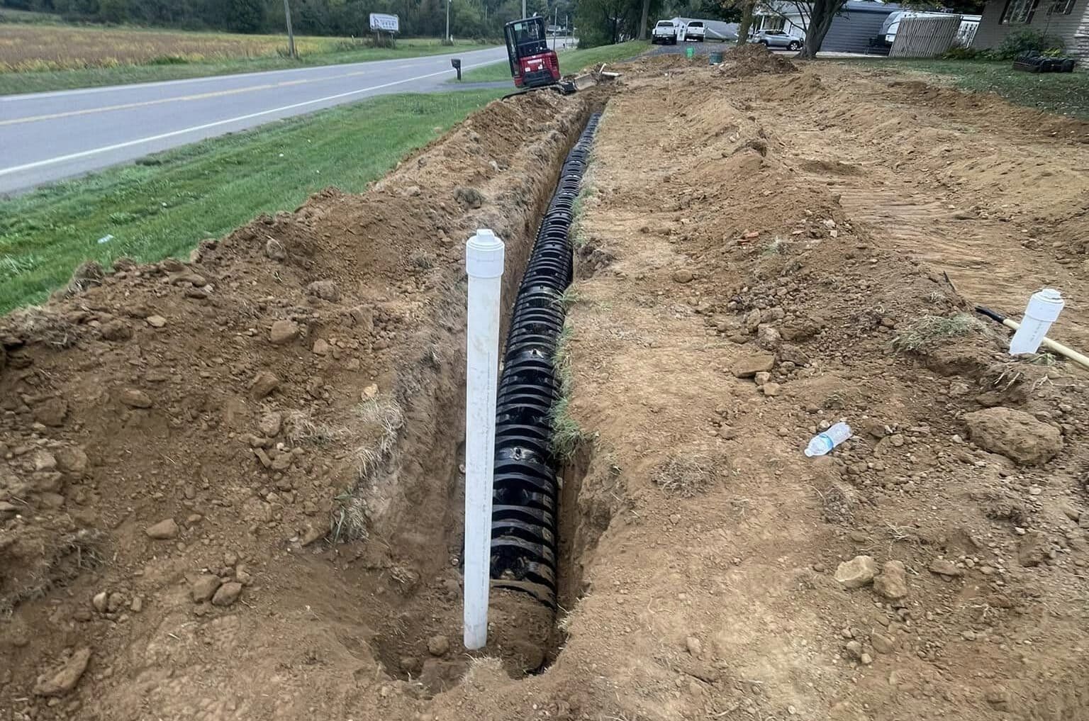 Drain Bros llc works on a home excavation project, installing drainage pipes for better water control in a yard.