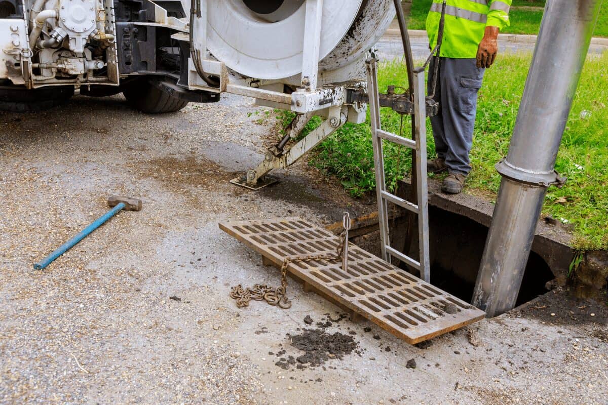 A Drain Bros llc worker checks an open storm drain, showing they fix and maintain city drains for safety and cleanliness.