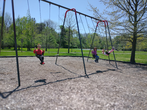 Kids play on swings in a park while Drain Bros llc workers install drainage to keep the playground safe and dry.