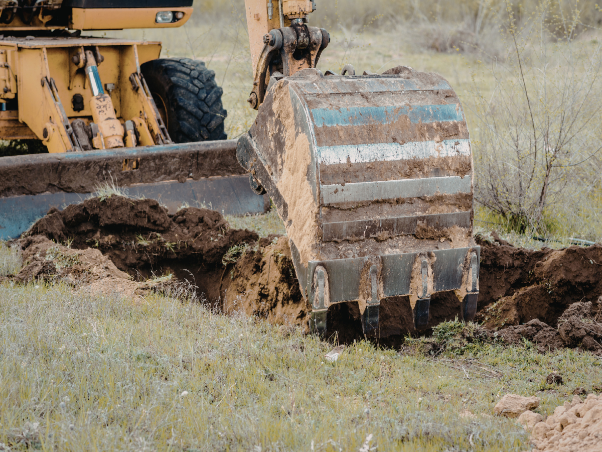 Drain Bros llc installing a septic system with machinery, preparing the ground for proper waste management.