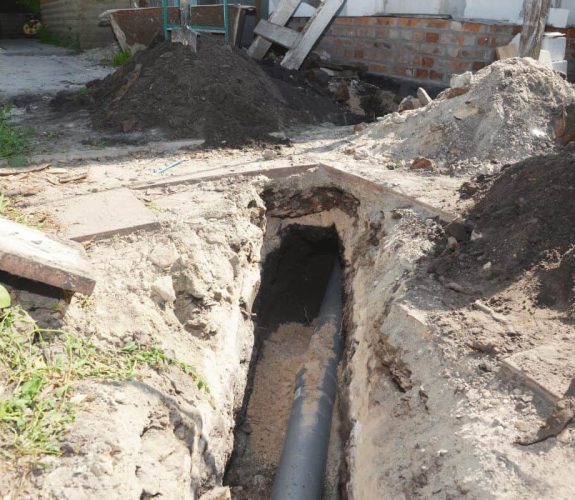 Drain Bros llc shows residential excavation with a pipe installation project in progress outside a building.